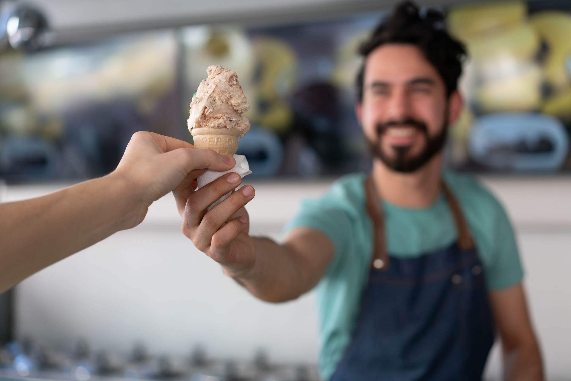 Male worker serving an ice cream to an costumer at the ice cream parlor